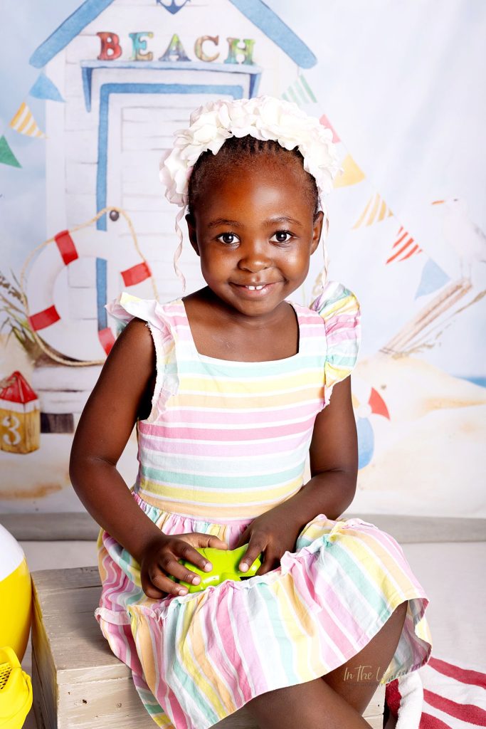 Nursery school photo of a girl smiling with a beach themed studio backdrop in Pretoria east